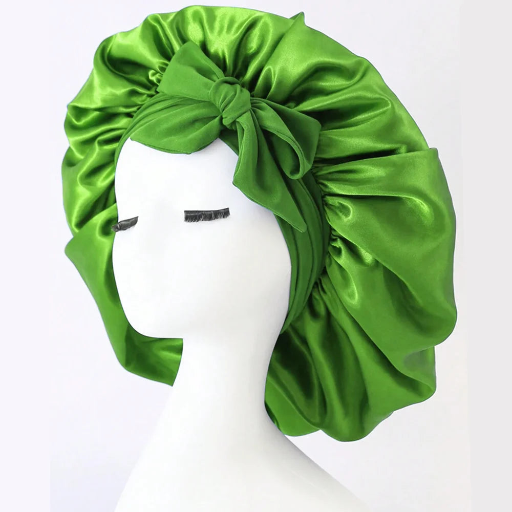 Green adjustable satin bonnet for sleeping with a large bow detail on a white mannequin head
