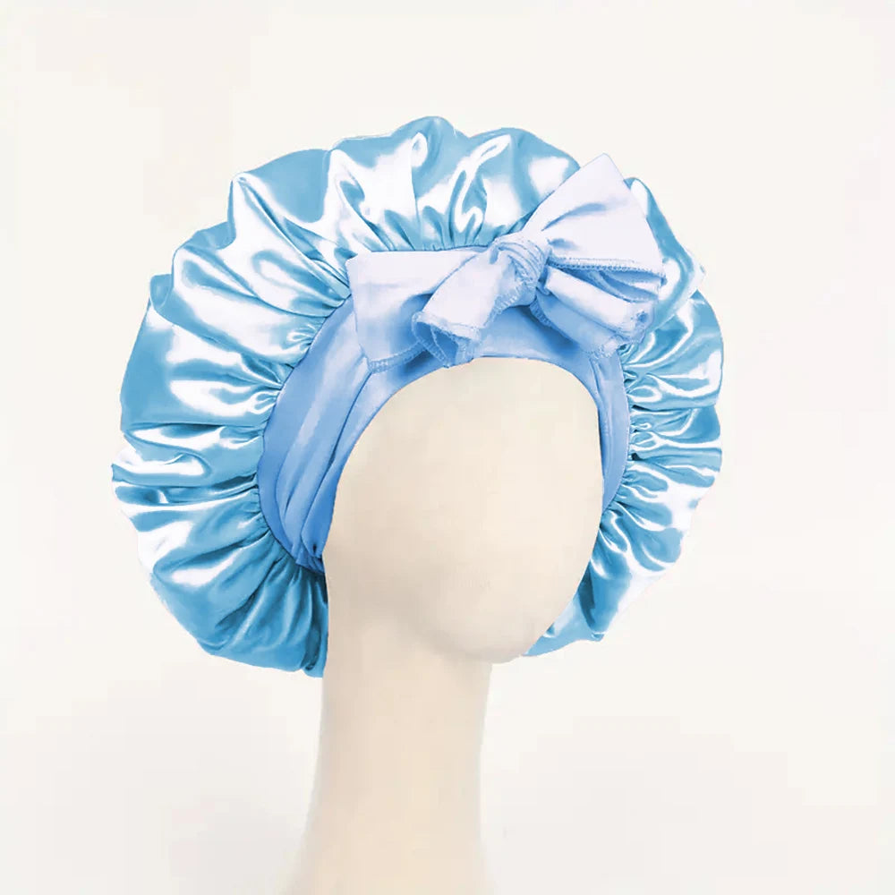 Light blue adjustable satin bonnet for sleeping with a large tied bow on a mannequin head