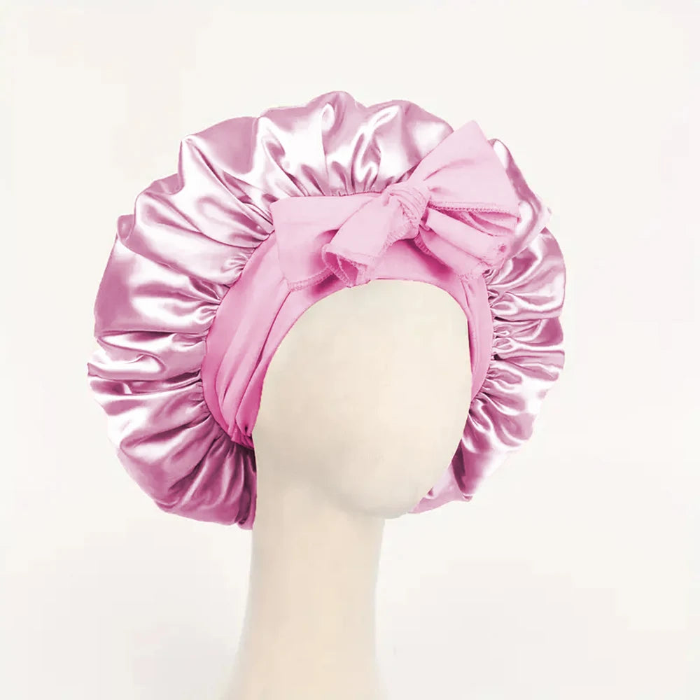 Pink adjustable satin bonnet for sleeping with a bow detail displayed on mannequin head