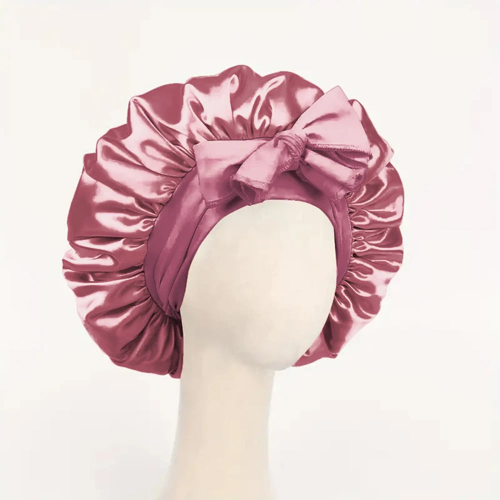 Pink adjustable satin bonnet for sleeping with a large bow on a mannequin head