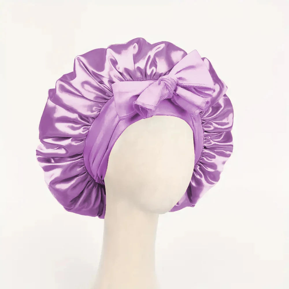 Purple adjustable satin bonnet for sleeping with large bow on a mannequin head