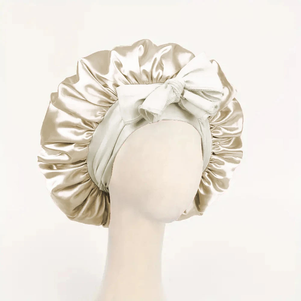 Cream adjustable satin bonnet for sleeping with a large bow detail on a mannequin head
