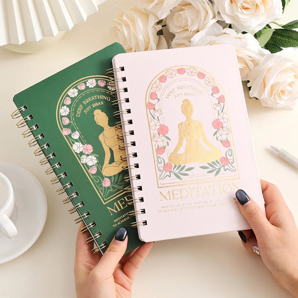 Meditation journal for mindfulness with floral design and gold seated figure on pink and green covers