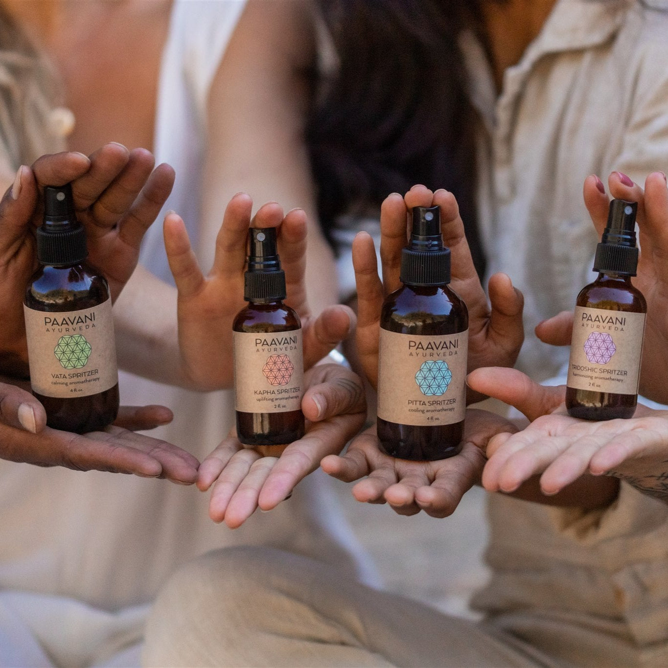 DC-PAAVANI Ayurveda Ayurvedic aromatherapy kit with four essential oil spray bottles held by diverse hands