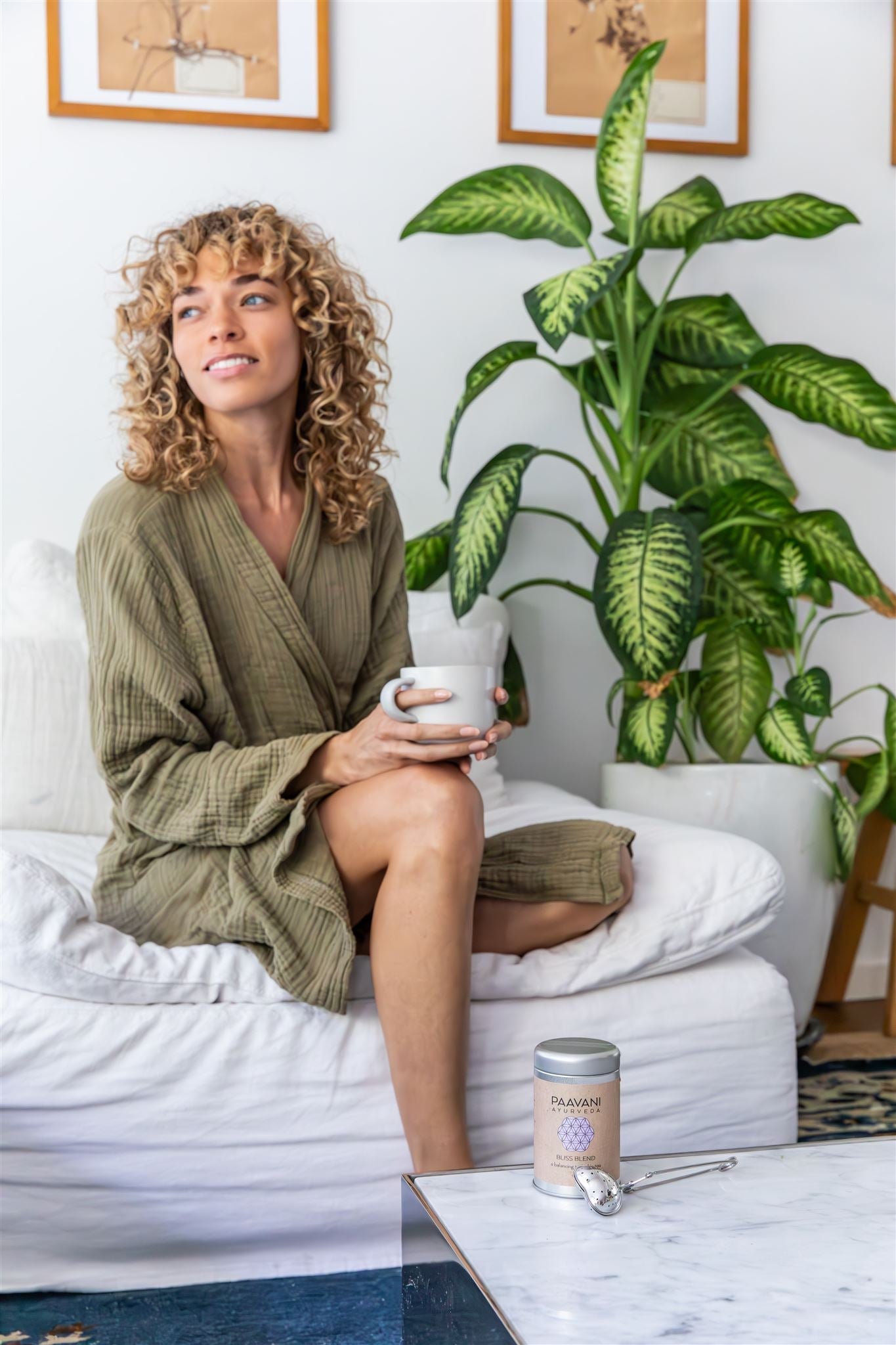 Woman relaxing on couch with a cup of tea and DC-PAAVANI Ayurveda organic loose leaf herbal tea container on table