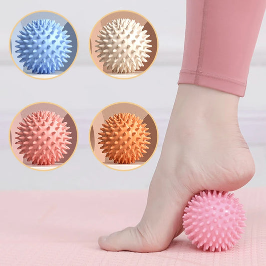 Spiky pink fascia ball for yoga and fitness rolled under foot with additional blue, white, coral, and orange balls