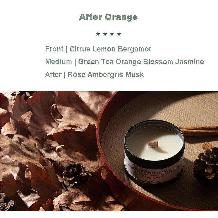 Scented candle with dried flowers in a black tin container placed on wooden tray with pine cones and leaves
