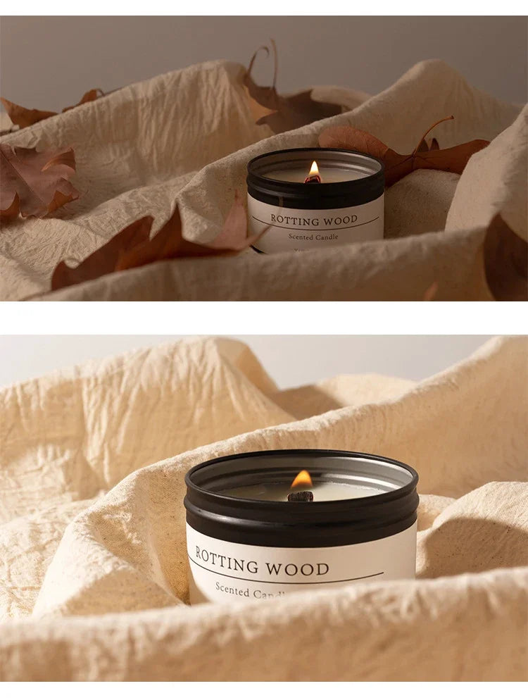 Scented candle with dried flowers in a black tin labeled Rotting Wood surrounded by beige fabric and dried leaves