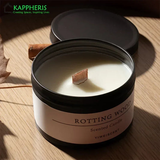 Scented candle with dried flowers in a black jar on a wooden surface with lid off