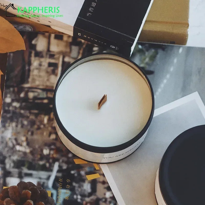 White scented candle with dried flowers in a black tin container on a magazine page