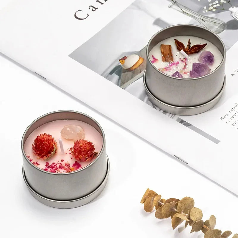 Two scented candles with dried flowers in silver tins on white background with decorative dried plants