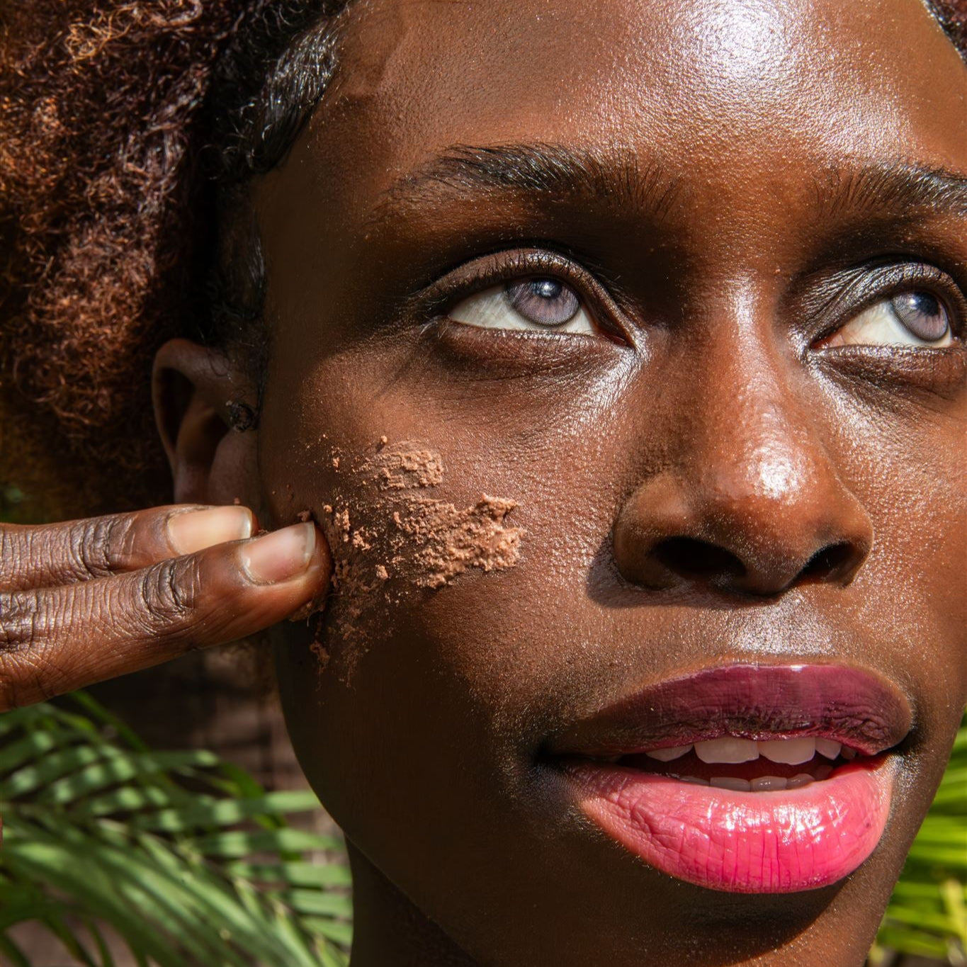 Close-up of woman applying ayurvedic cleanser for dry skin to her cheek outdoors