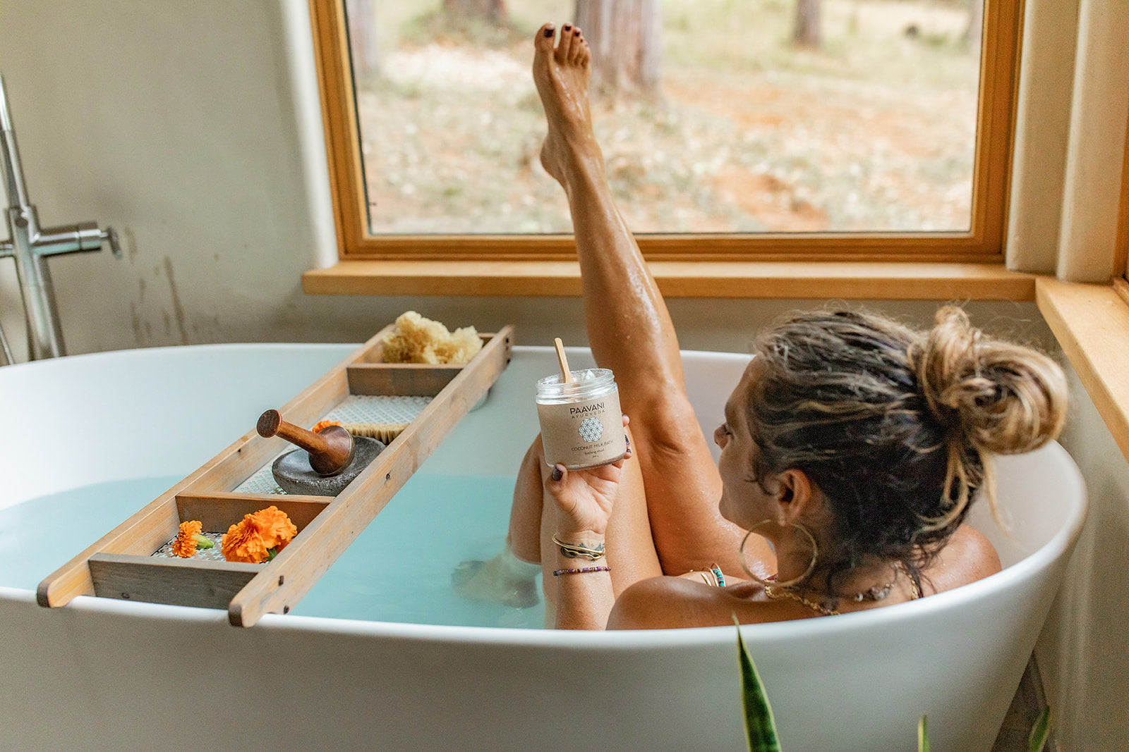 Woman relaxing in bathtub holding jar of Ayurvedic coconut milk bath by DC-PAAVANI Ayurveda