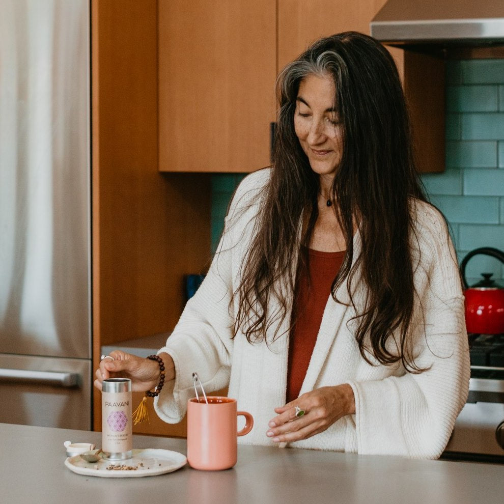 Woman preparing ayurvedic menopause support tea from DC-PAAVANI Ayurveda in cozy kitchen setting