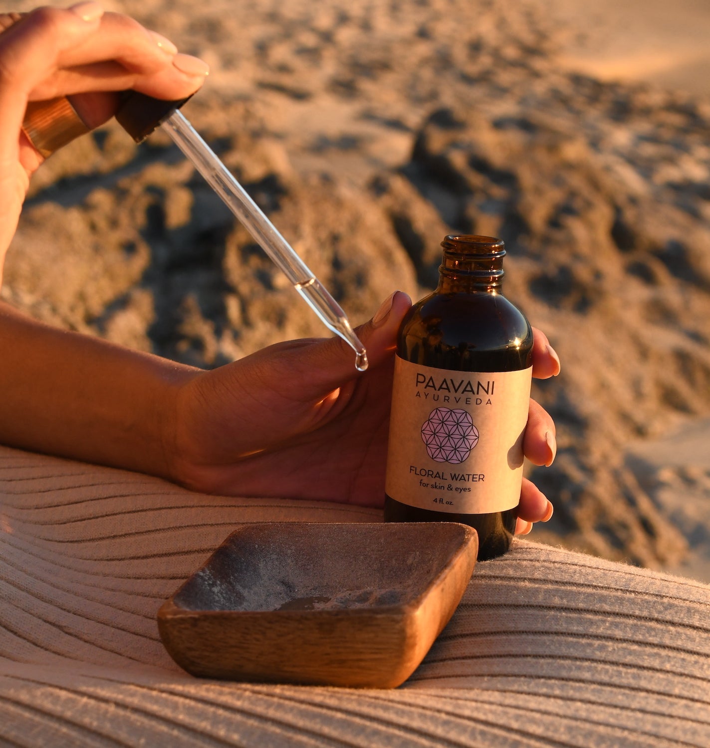 Person holding Paavani Ayurveda floral water bottle and dropper demonstrating Ayurvedic skin care class outdoors