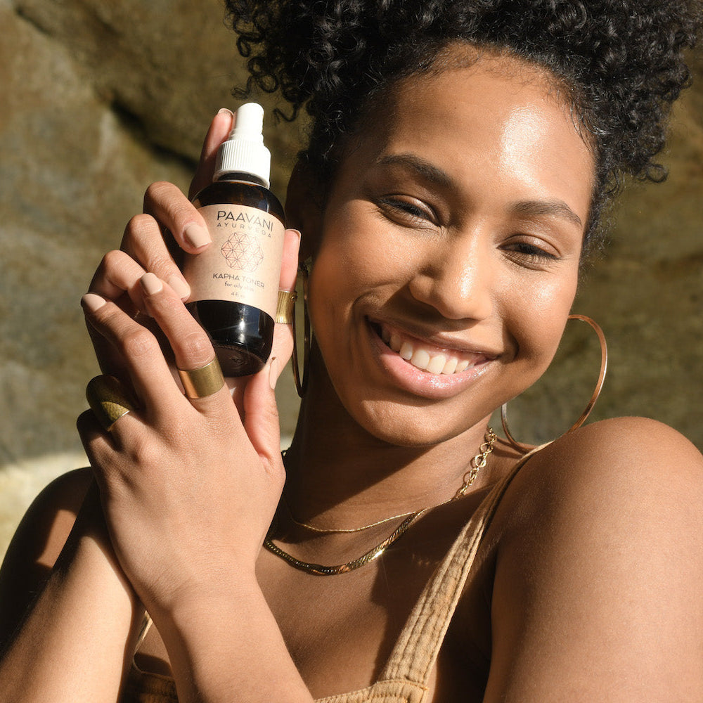 Smiling woman holding Ayurvedic skin care product during DC-PAAVANI Ayurveda Ayurvedic skin care class