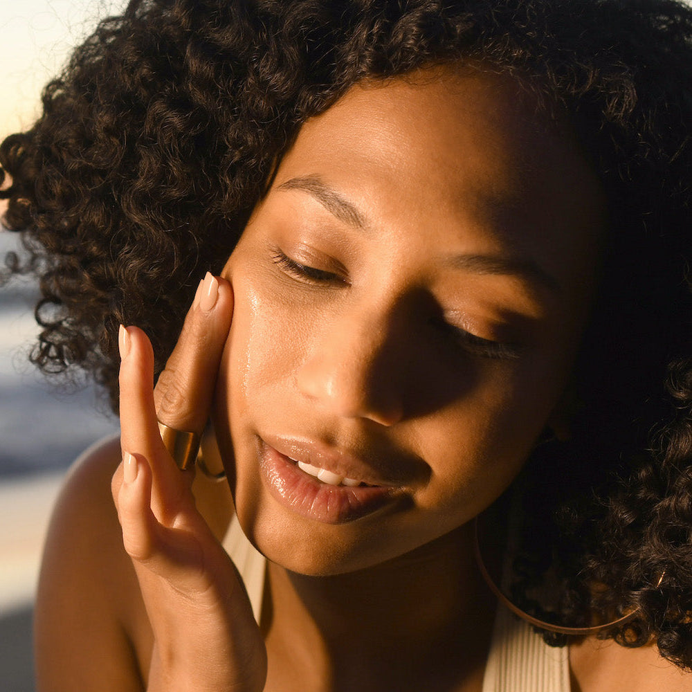 Close-up of woman with glowing skin gently touching her face for Ayurvedic skin care class