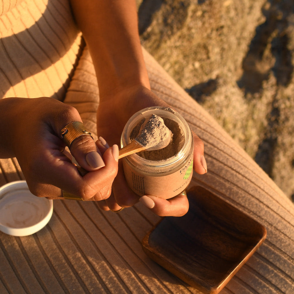 Hands holding jar of Ayurvedic face mask powder in sunlight for Ayurvedic skin care class