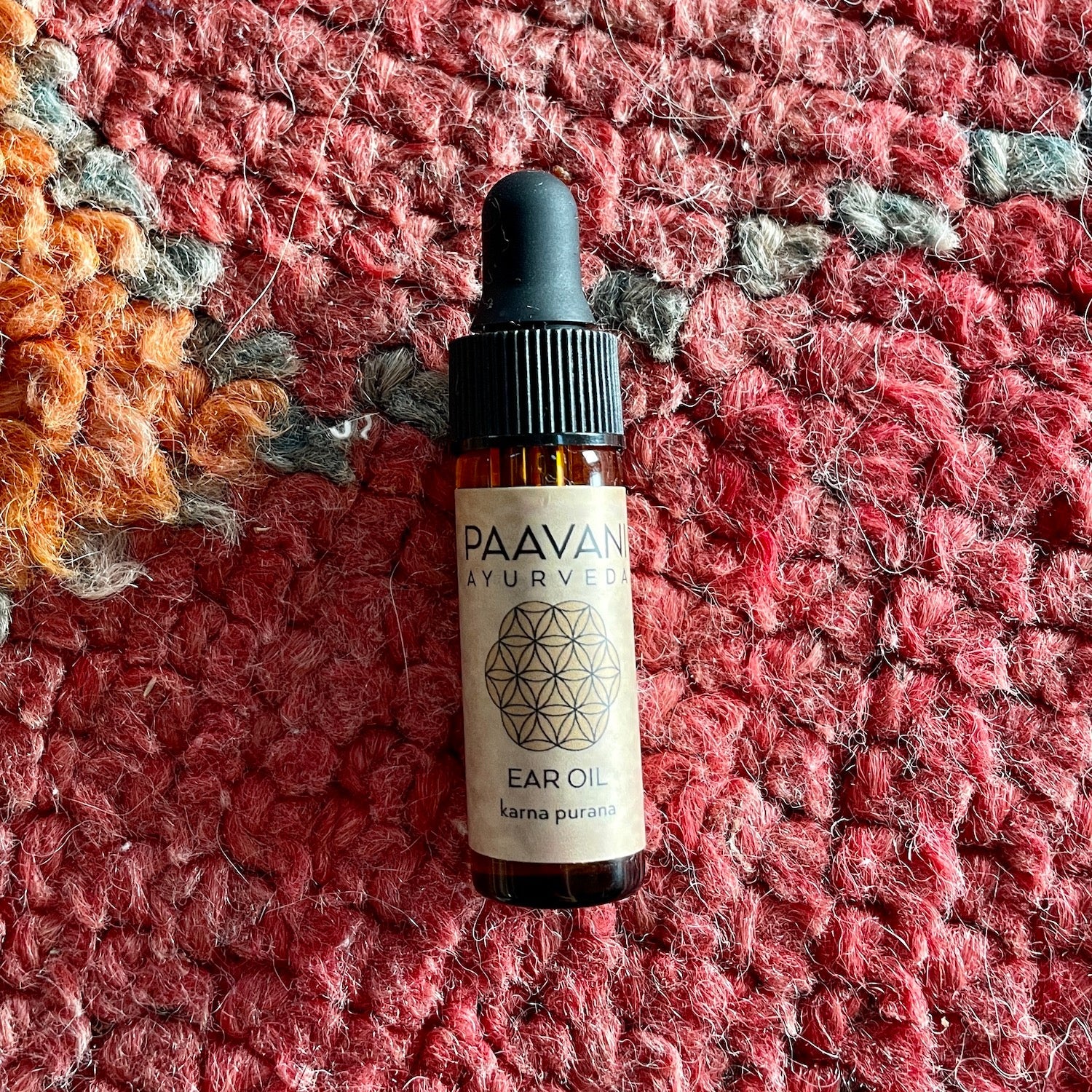 DC-PAAVANI Ayurveda ear oil bottle from Ayurvedic winter wellness kit on red textured fabric