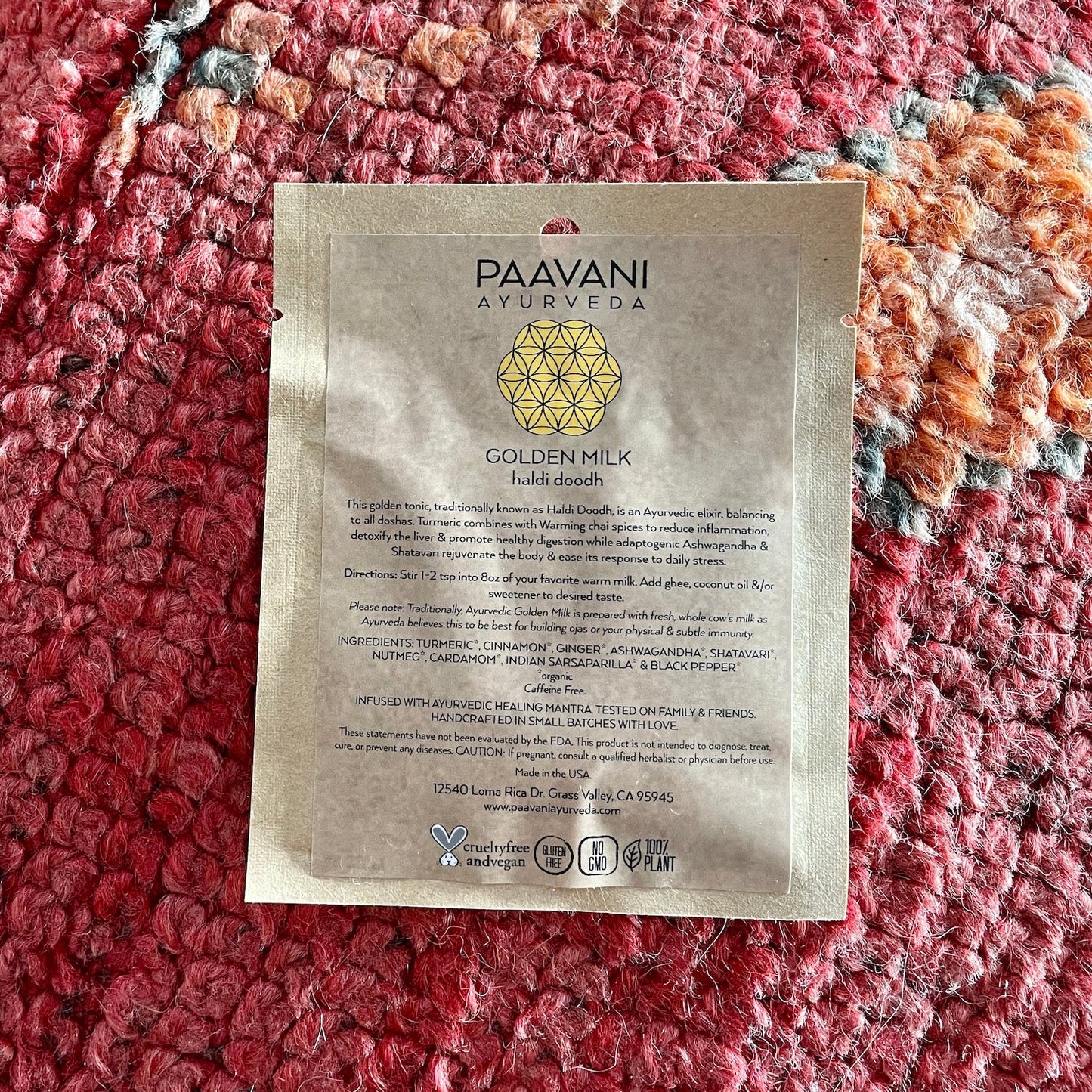 PAAVANI Ayurveda Golden Milk Haldi Doodh packet from Ayurvedic winter wellness kit on textured red surface