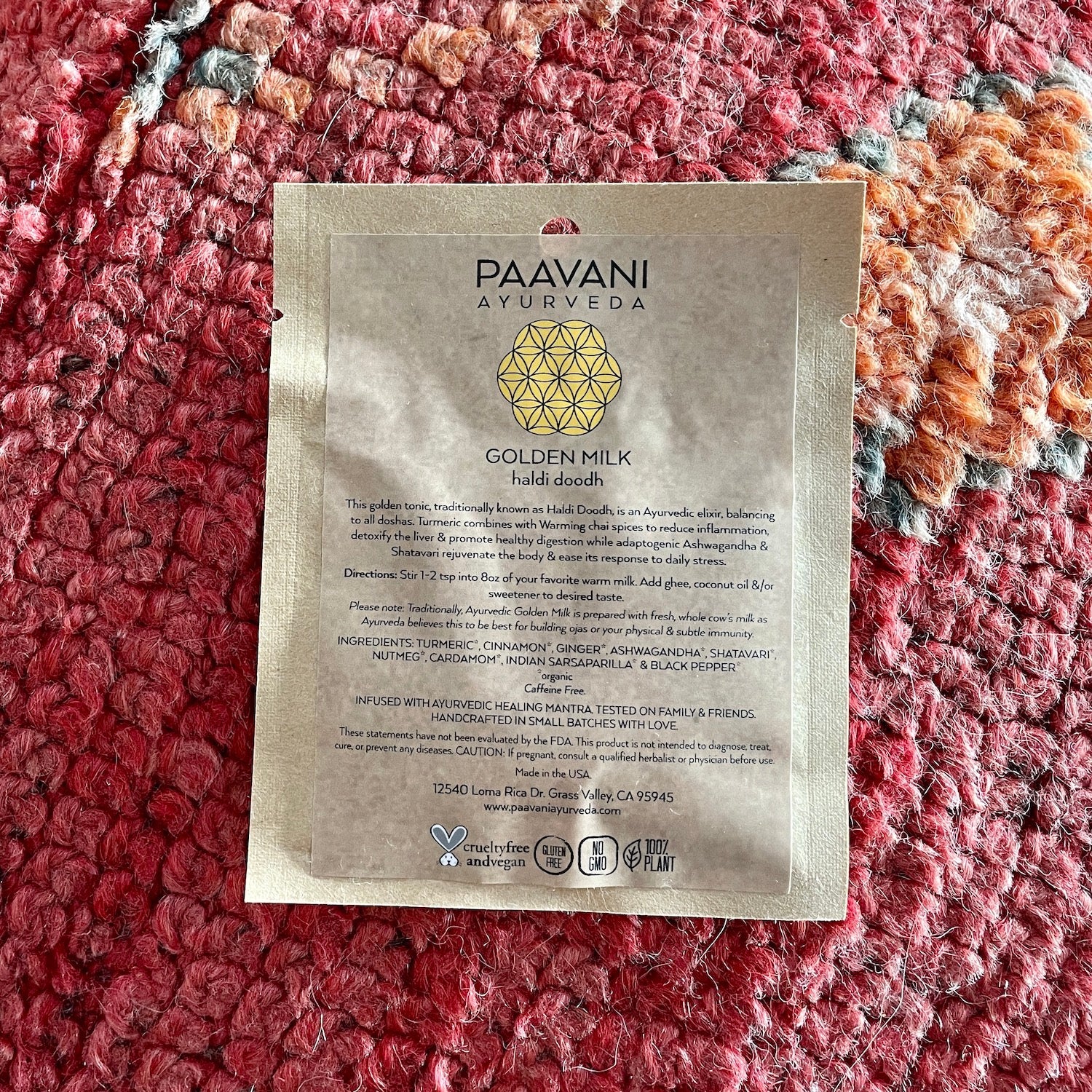 PAAVANI Ayurveda Golden Milk Haldi Doodh packet from Ayurvedic winter wellness kit on textured red surface