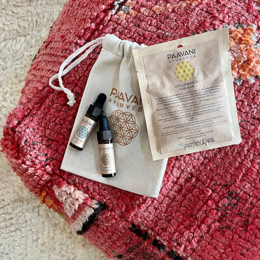DC-PAAVANI Ayurveda Ayurvedic winter wellness kit with herbal oils and golden milk sachet on a red textured cloth