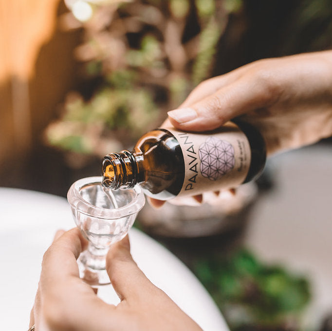 DC-PAAVANI Ayurveda bottle pouring oil into a glass cup for Dinacharya ritual kit for daily wellness