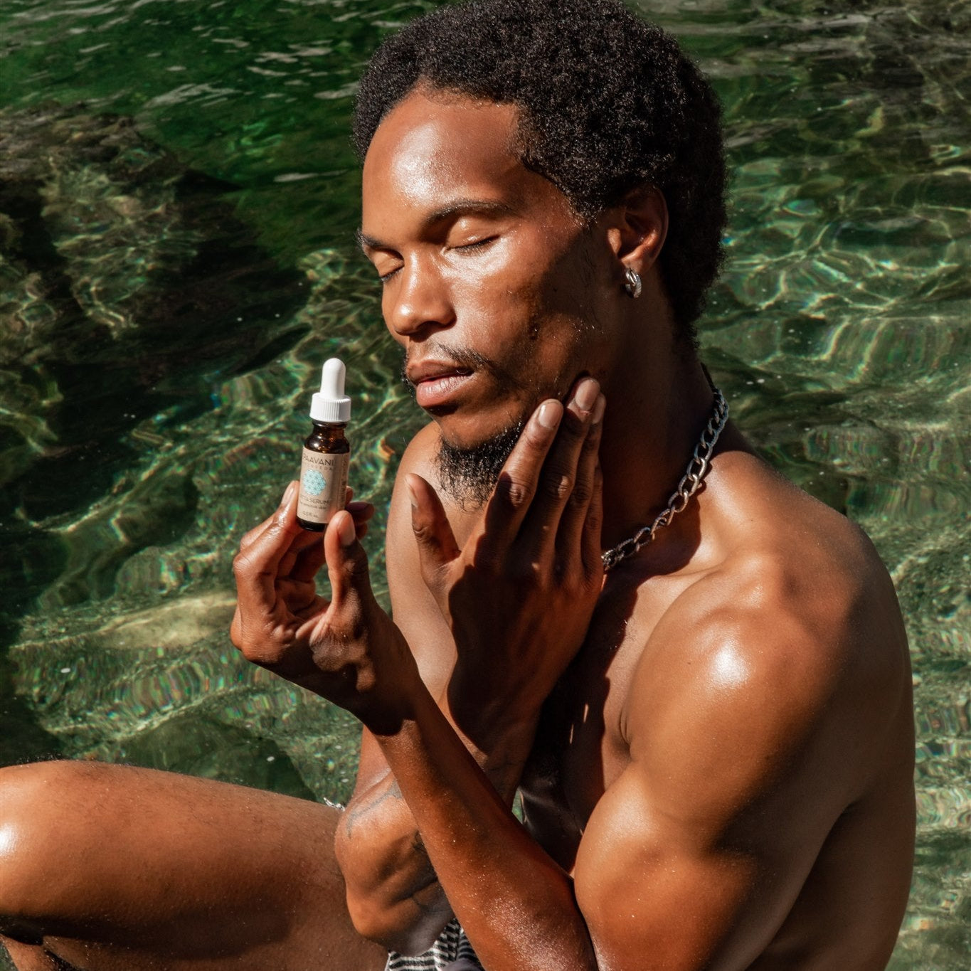 Man applying skincare from Pitta facial ritual set by DC-PAAVANI Ayurveda near water background