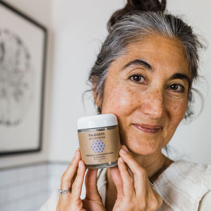 Woman holding a jar of Paavani Ayurveda Tridoshic Cleanser from the tridoshic facial ritual kit