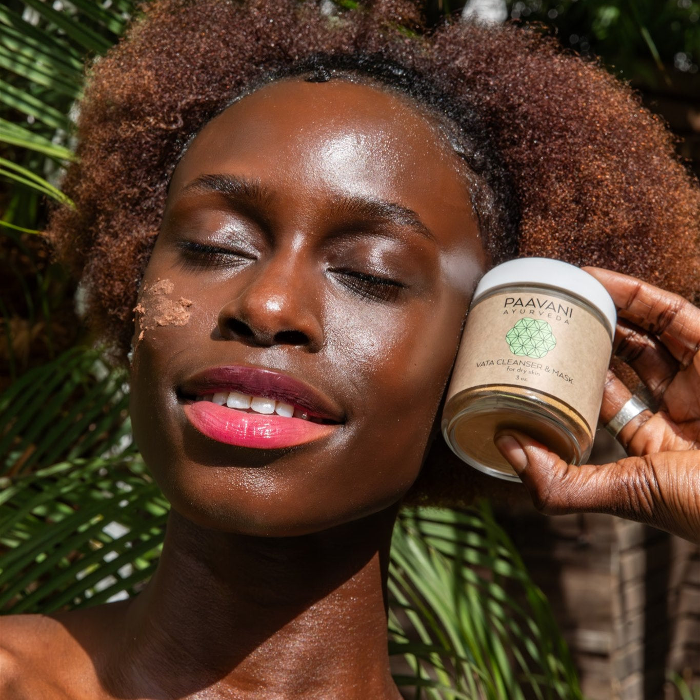 Woman with glowing skin holding DC-PAAVANI Ayurveda vata facial ritual set cream outdoors