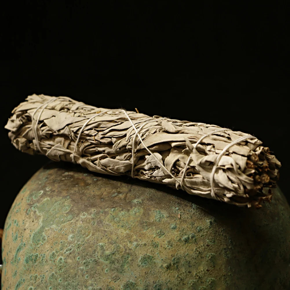 Palo santo white sage smudge stick tied with string resting on a textured green surface