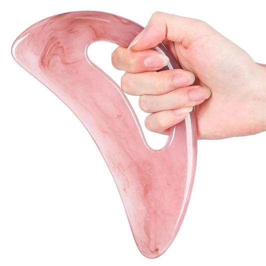 Hand holding a pink rose quartz gua sha massage tool for facial and body skincare