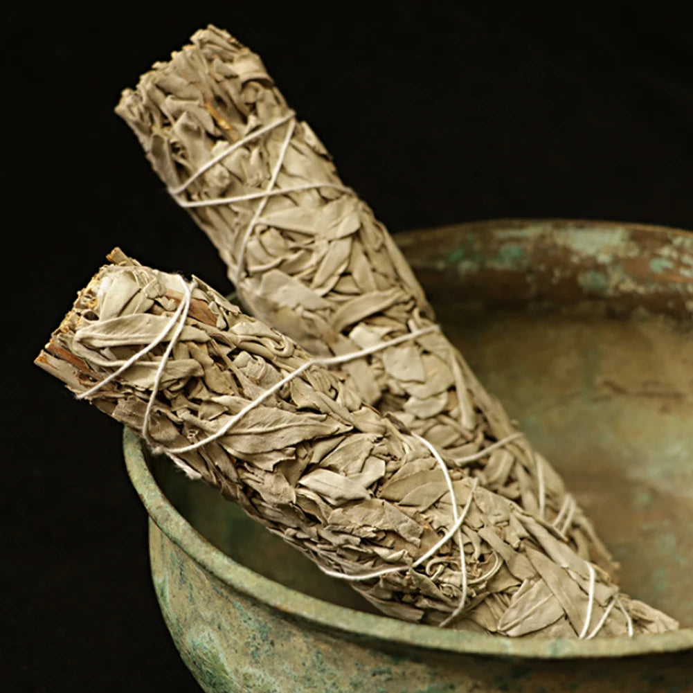 Two palo santo white sage smudge sticks resting in a rustic metal bowl by Sacred Self Wellness